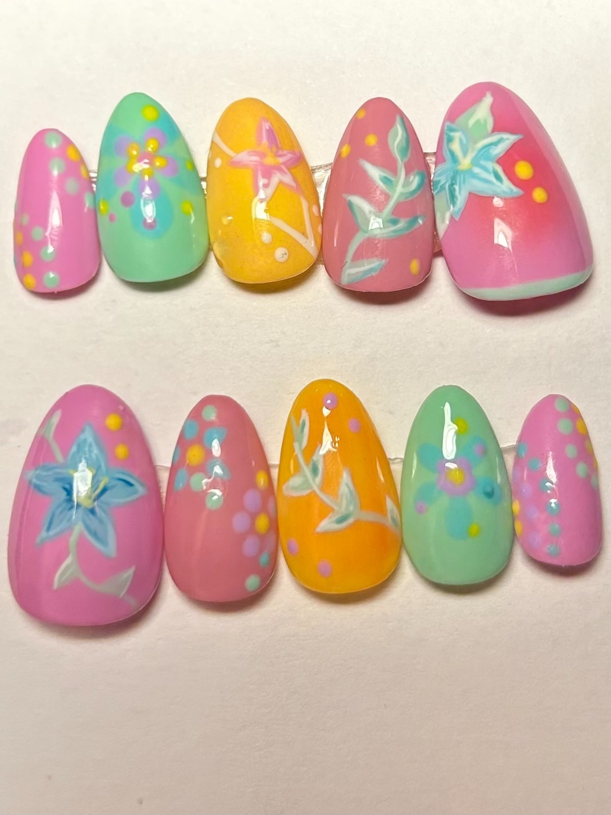 Multi-colored floral nail art with blue flowers and leaves with pink and yellow.